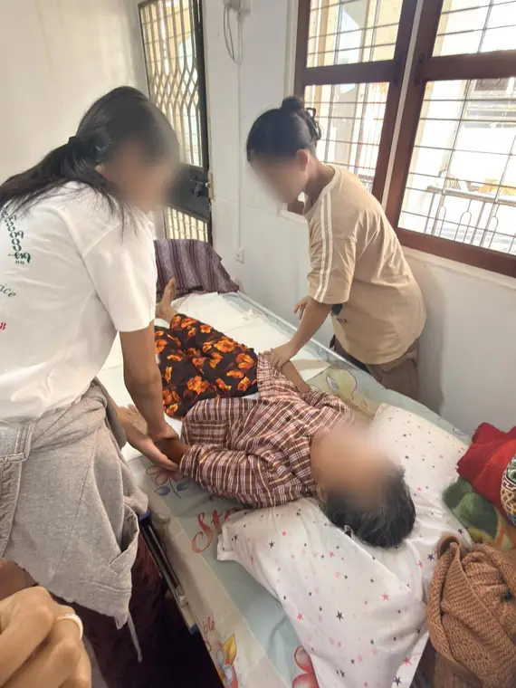 VAI student volunteers, bedside care for an elderly resident, Mandalay