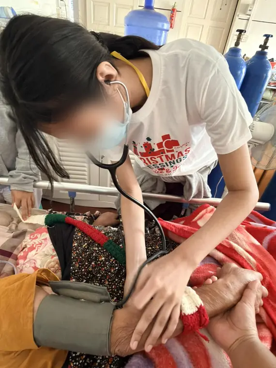 VAI student volunteers, checking a resident's blood pressure, Mandalay