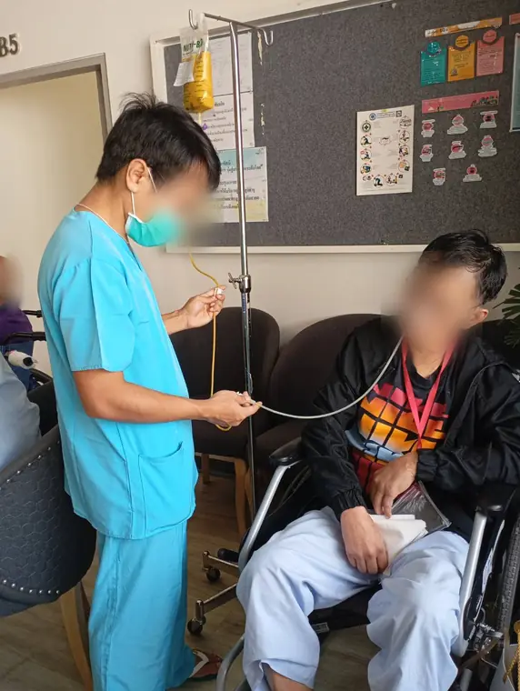 VAI student volunteers, supporting a resident on oxygen therapy, Bangkok